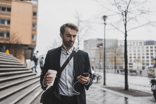 man with his earphones in and looking at his phone