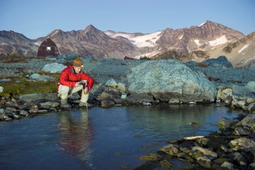 man collecting water from a small lake